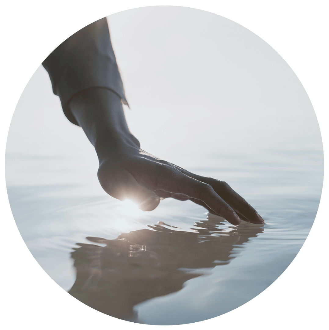 Eine sich im Wasser reflektierende Hand, die mit den Fingerspitzen den Wasserspiegel berührt.