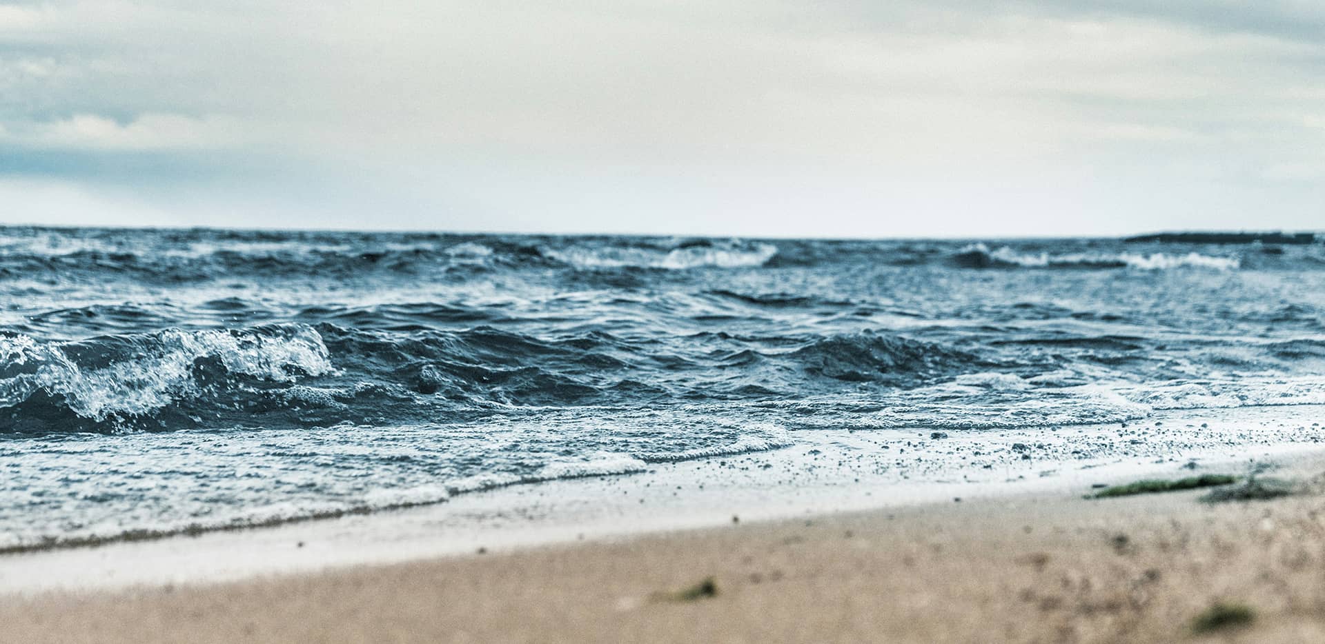 An einem Natur-Sandstrand aufschlagende Wellen.