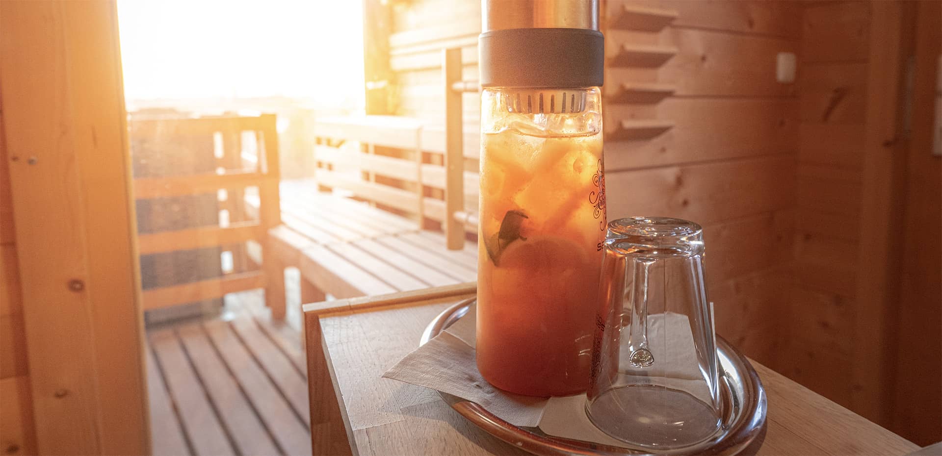 Eiskalter Samova Eistee in der Dachterrassensauna in goldenem Licht.