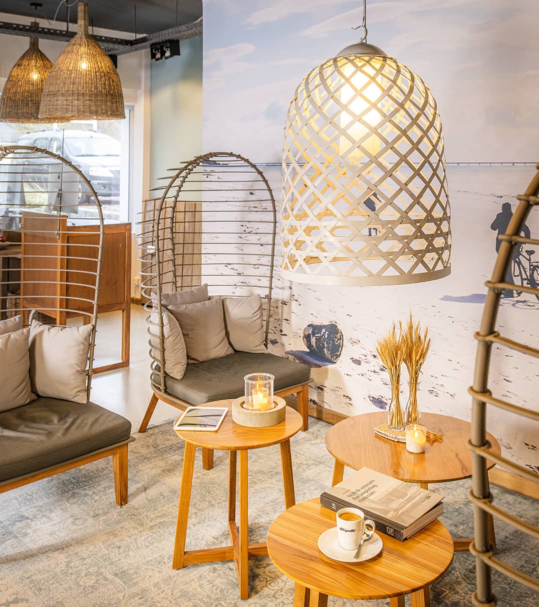 Gemütlich beleuchtete Hotellobby mit drei niedrigen Tischchen und eco-schicken Stühlen.