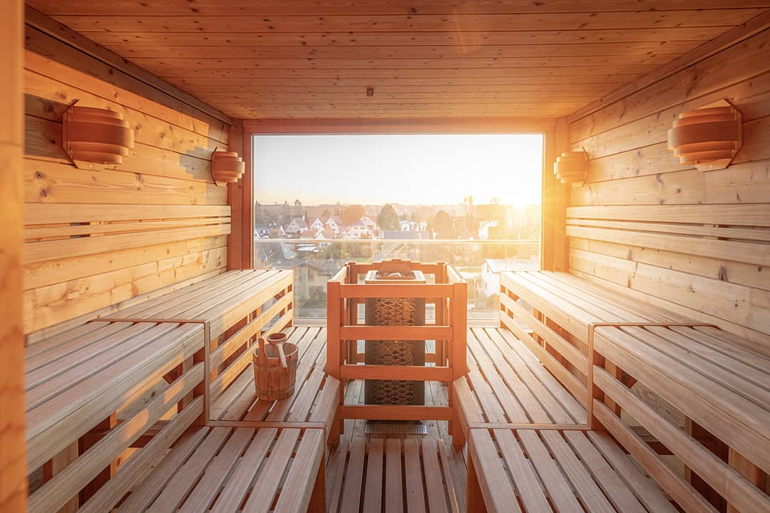 Innenansicht der Dachterrassensauna im einfallenden Sonnenlicht durch das Panoramafenster.