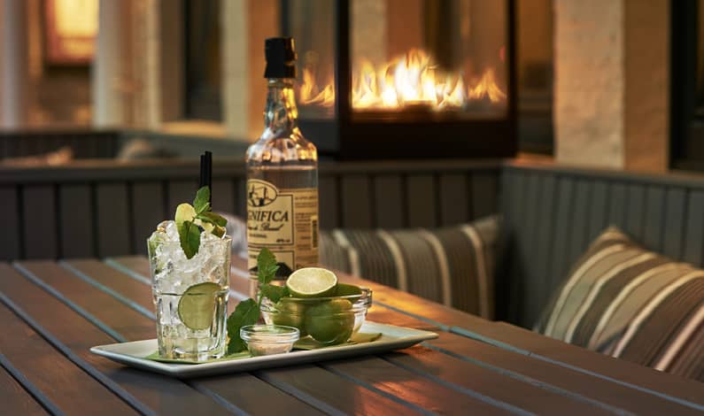 Sitzecke im Außenbereich mit Feuerspiel und alkoholischem Aperitif mit Limetten.