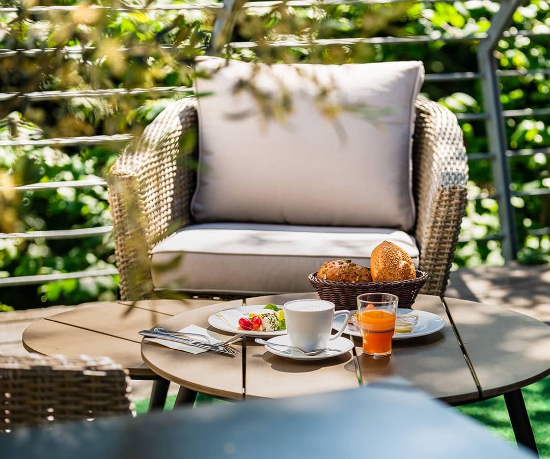 Kleines Frühstück in der sonnigen Loungeecke einer Terrasse.