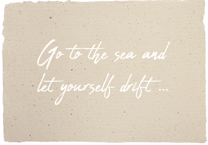 Cursive writing on a paper with the text „travel to the sea and let yourself drift away”